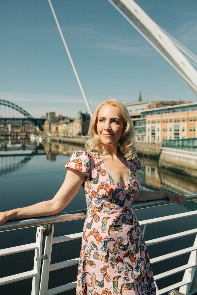 Photograph of Prof Katy Shaw against a backdrop of the bridges crossing the river Tyne near Newcastle